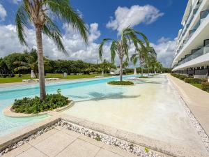 Una piscina con palmeras al lado de un edificio. en Cana Rock Penthouse Golf Views & Infinity Pool, en Punta Cana