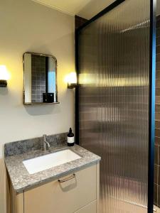 a bathroom with a sink and a shower with a mirror at House Up On Ramberget In Mollösund in Mollösund