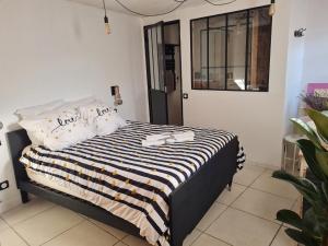 Un dormitorio con una cama con una manta de rayas blancas y negras. en La Fontaine, en Beaumont-du-Ventoux