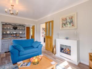a living room with a blue couch and a fireplace at Paddock End in Great Plumstead