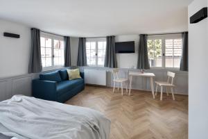a bedroom with a blue couch and a table and chairs at Krone Hard - self check-in in Hard