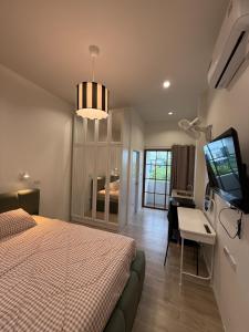 a bedroom with a bed and a desk and a television at Minimal Apartment in Central of city Near Central 1 km in Nakhon Pathom
