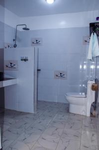 a white bathroom with a toilet and a sink at Daisy Apptment in Malindi
