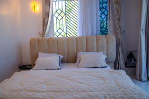 a large bed with a large headboard and two pillows at Daisy Apptment in Malindi