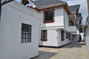 ein weißes Haus mit schwarzen Fenstern und einer Auffahrt in der Unterkunft White House II in Naivasha