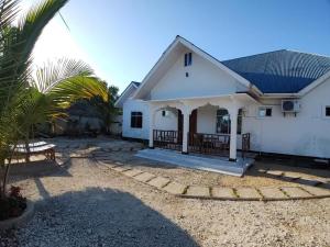 a white house with a palm tree in front of it at Malaika White House Apartment & Spa in Kiwengwa