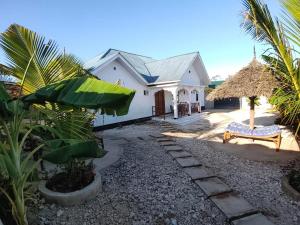 a white house with a bench in front of it at Malaika White House Apartment & Spa in Kiwengwa