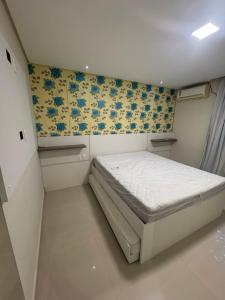 ein kleines Schlafzimmer mit einem Bett und Blumentapete in der Unterkunft Casa em Tamandaré praia in Tamandaré