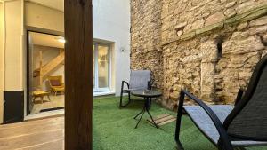 a patio with chairs and a table and a stone wall at Le petit Cocon in Nevers