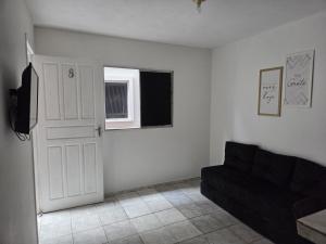 een woonkamer met een zwarte bank en een deur bij Casa com Quarto e Garagem, Alto da Cruz, Camaçari in Camaçari