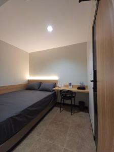 a bedroom with a bed and a desk at Hello Inn permata hijau in Stasiun Tawang