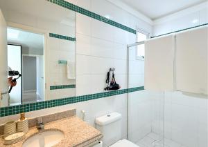 a bathroom with a sink and a toilet and a mirror at RefugioBacutia- Prédio FRENTE MAR Bacutia- 6 pessoas- 3 Quartos com AR sendo 1 suite - varanda- sala de estar e jantar Ampla -Piscina e Sauna no Prédio in Guarapari