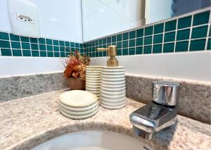 a bathroom counter with a sink with plates and a faucet at RefugioBacutia- Prédio FRENTE MAR Bacutia- 6 pessoas- 3 Quartos com AR sendo 1 suite - varanda- sala de estar e jantar Ampla -Piscina e Sauna no Prédio in Guarapari