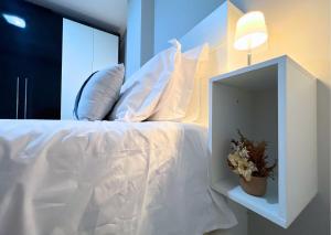 a bed with a white comforter and pillows at RefugioBacutia- Prédio FRENTE MAR Bacutia- 6 pessoas- 3 Quartos com AR sendo 1 suite - varanda- sala de estar e jantar Ampla -Piscina e Sauna no Prédio in Guarapari