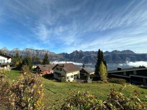 ein Haus auf einem Hügel mit Bergen im Hintergrund in der Unterkunft Mätzwiesen Höckli - CharmingStay in Flumserberg