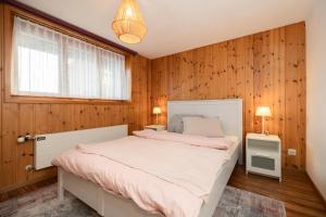 Schlafzimmer mit einem Bett mit Holzwänden und einem Fenster in der Unterkunft Mätzwiesen Höckli - CharmingStay in Flumserberg