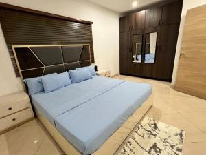 a bedroom with a large bed with blue pillows at The Elegant 3BedRoom Home in Community 25, Tema in Dawhwenya