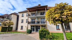 un grand bâtiment blanc avec un arbre devant dans l'établissement Gîte Le 47, à Levernois