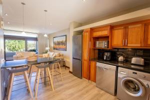 eine Küche und ein Wohnzimmer mit einem Tisch und einer Waschmaschine in der Unterkunft Terrace Tranquility at Oubaai Golf Estate in Herolds Bay