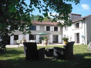 a view of a house with chairs in the yard at Gîte Des Roties in Poncins