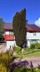 Un edificio con un gran árbol delante. en Cabañas Casona Italiana, en Lago Ranco