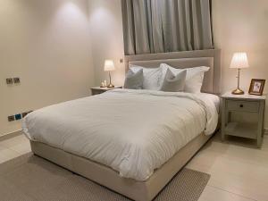 a bedroom with a large white bed with white pillows at شقة بغرفتي نوم وغرفة معيشة in Jeddah