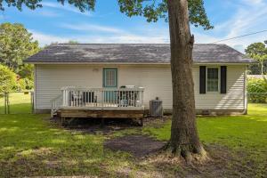 a house with a wooden bench next to a tree at Pet-Friendly 3 BR Home with King Bed and Fenced Yard Near Downtown in New Bern
