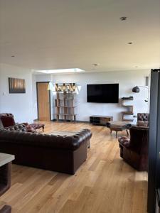 a living room with a couch and a flat screen tv at Luxurious, Unique & Elegant Cottage with Hot Tub in Ollach