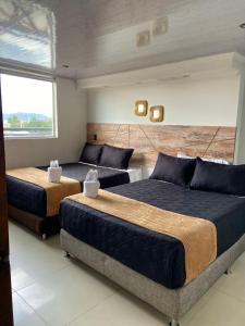 FunzaにあるHotel Funza Realのベッドが2つと大きな窓がある寝室