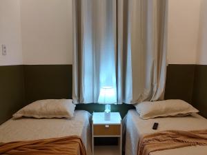 a bedroom with two beds and a lamp on a table at Studio 101 Cop 30 in Belém