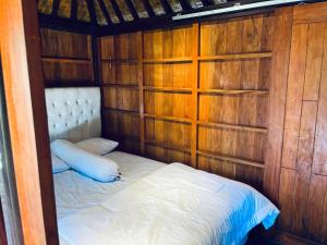 a small bed in a room with wooden walls at Arina's Cabin in Aik Berik