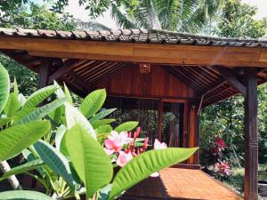 a wooden building with a wooden deck with flowers at Arina's Cabin in Aik Berik