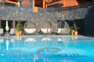 a swimming pool with wicker chairs and a hotel at Hotel Arena Castillo in Caleta De Fuste
