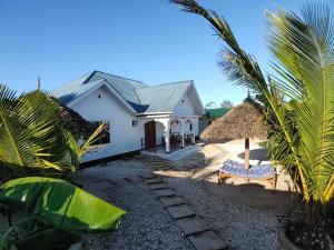 a white house with a thatch roof at Malaika White House Apartment & Spa in Kiwengwa