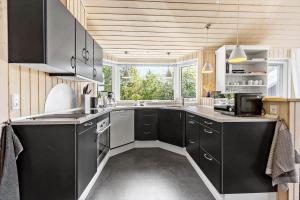 a kitchen with black cabinets and a large window at 8424-Knebel-Rastestedet-46 in Knebel +16 photos
