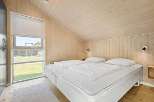 a large white bed in a room with a window at 8424-Knebel-Rastestedet-46 in Knebel