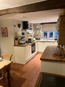 a large kitchen with white cabinets and a table at Miners Cottage in Bakewell