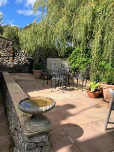a stone patio with a bird bath and tables and chairs at Miners Cottage in Bakewell