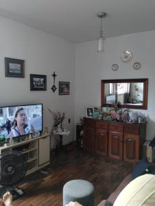 a living room with a tv and a woman on the screen at Suíte Aconchegante Centro COP30 in Belém