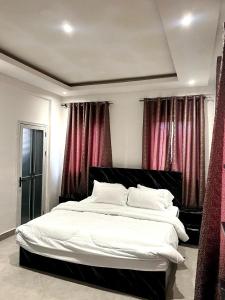 a bedroom with a large white bed with red curtains at Helios Towers in Accra