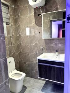 a bathroom with a toilet and a sink and a mirror at Helios Towers in Accra