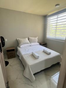 a bedroom with a bed with two towels on it at Moderno Apt en Reserva del Peñón en Girardot in Girardot +19 photos