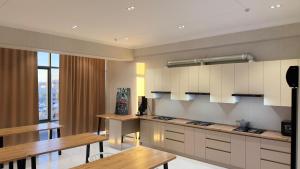 a large kitchen with white cabinets and wooden tables at Arzum Hostel in Tashkent
