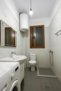 a white bathroom with a toilet and a sink at Trumpets Apartment in Tirana