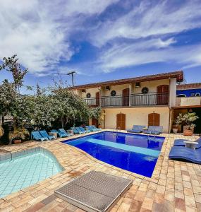 a swimming pool with blue chairs and a house at Pousada Ilha Vitoria in Ubatuba +56 photos