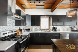 a kitchen with black cabinets and a stove top oven at Front LAKE Simon HOT TUB 6br 17p BEACH private in Lac-Simon