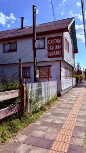 a white building with a sign on the side of it at Cabañas Casona Italiana in Lago Ranco