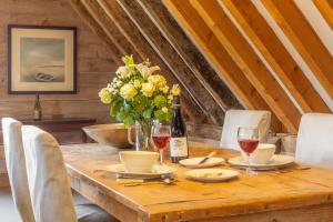 une table en bois avec des verres à vin et un vase de fleurs dans l'établissement Belchamp Hall Hayloft, à Belchamp Otten 24 autres photos