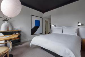 a bedroom with a large white bed and a table at One Hundred Shoreditch in London