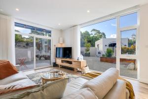 a living room with a couch and a tv and large windows at Magnolia - Your Private Luxury Escape Awaits in Scamander